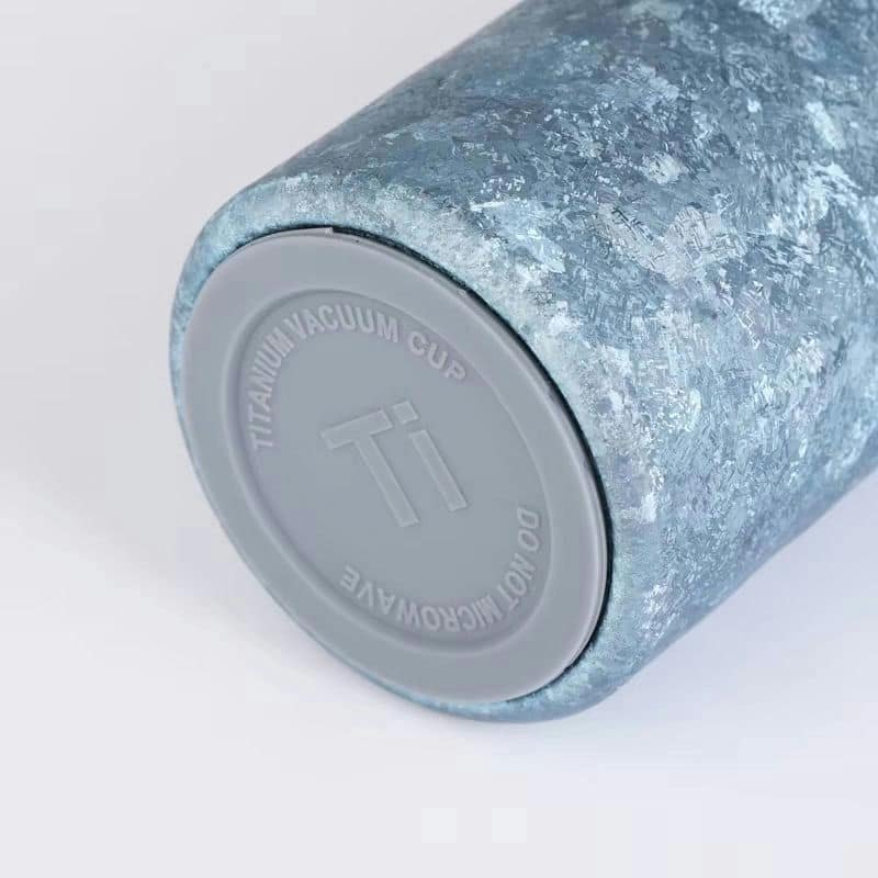 Close-up of blue ice-crack finish on a pure titanium cup