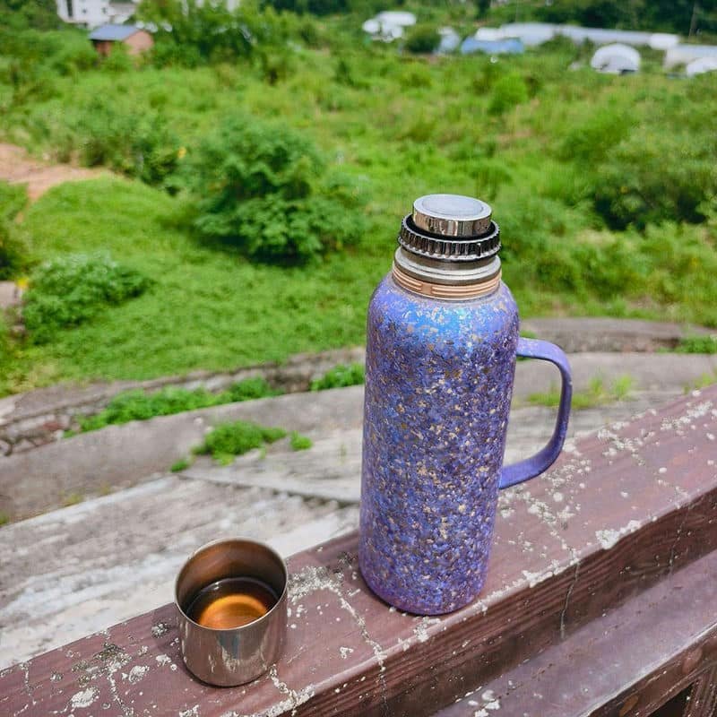 One-litre pure titanium vacuum bottle with handle on a camping trip